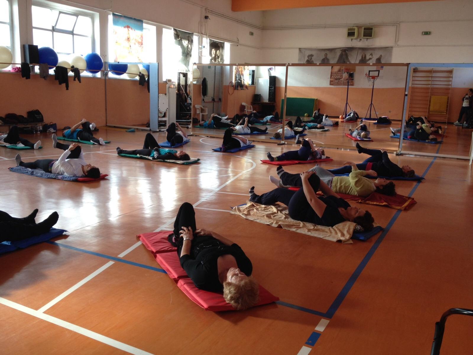 Gruppo di persone durante una sessione di ginnastica posturale sui tappetini in palestra